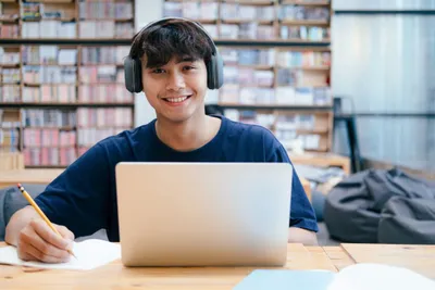 pelajar sma belajar di depan laptop dengan memakai headset
