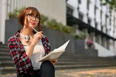 perempuan membawa notebook dan headset