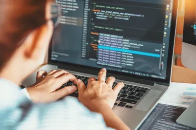 Seseorang sedang mengerjakan coding di laptop.