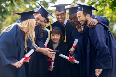Sekelompok orang sedang memakai toga wisuda dan memegang gulungan kertas.