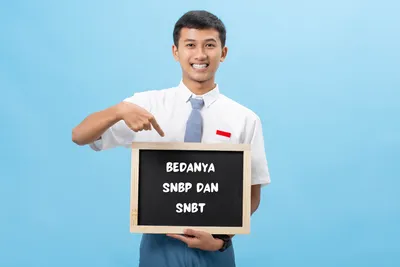 seorang siswa SMA sedang memegang papan kecil dengan tulisan 'bedanya SNBP dan SNBT'