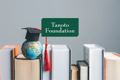 deretan buku tebal dengan globe pakai toga di atasnya, ada logo Tanoto Foundation