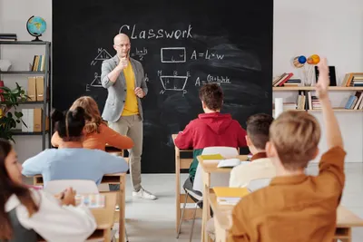 Guru sedang mengajar di depan kelas.